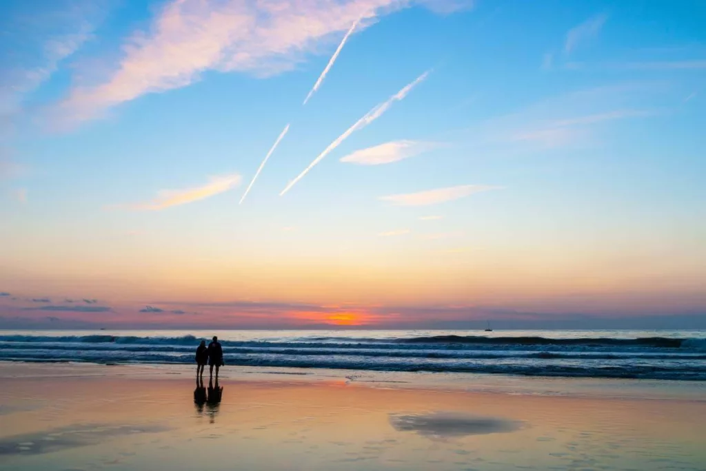 Koppel geniet van zonsondergang op het strand tijdens een verlengd weekend in België